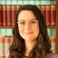 Portrait von Ada vor einem etwas verschwommenen Bücherregal im Hintergrund